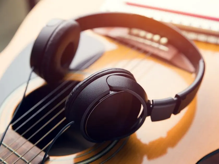 ameliorer-oreille-musicale-ecouteur Guitariste utilisant un casque pour améliorer son oreille musicale